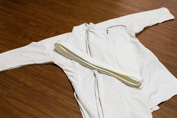 A white belt and Gi ( martial arts uniform ) on the wood floor