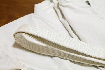 A white belt and Gi ( martial arts uniform ) on the wood floor