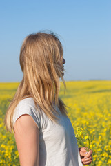 Naklejka na ściany i meble Young woman, blonde relaxes in a field of yellow flowers
