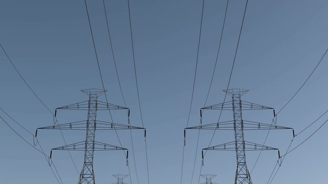 Pan of electrical power lines and pylons under sky. energy conservation conception. Electricity pylons and lines on a clear blue sky. loopable animation