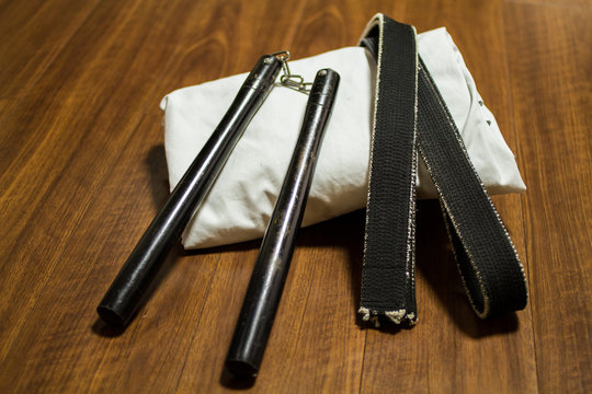 Nunchaku ( traditional okinawan karate's weapon) , black belt and Gi (japanese martial arts uniform) on the floor