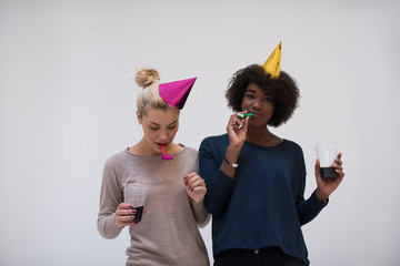 smiling women in party caps blowing to whistles