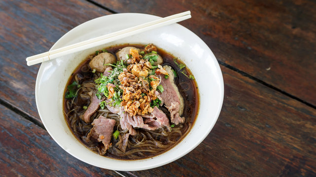 Noodles with pork on a wooden background (Thai noodles).