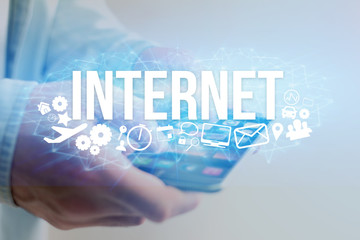 Concept of man holding futuristic interface with internet title and multimedia icons flying all around - Internet concept