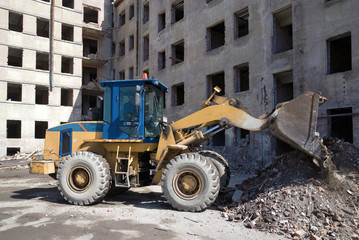 Fototapeta na wymiar Heavy forklift front loader is working on the reconstruction of an old residential house, Kronstadt