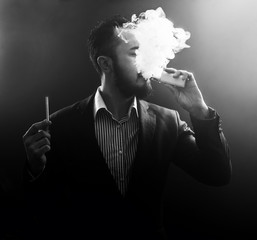 vaping man holding a mod and cigarette. A cloud of vapor.