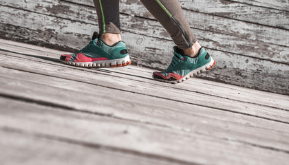 female legs in sneakers on a wooden background