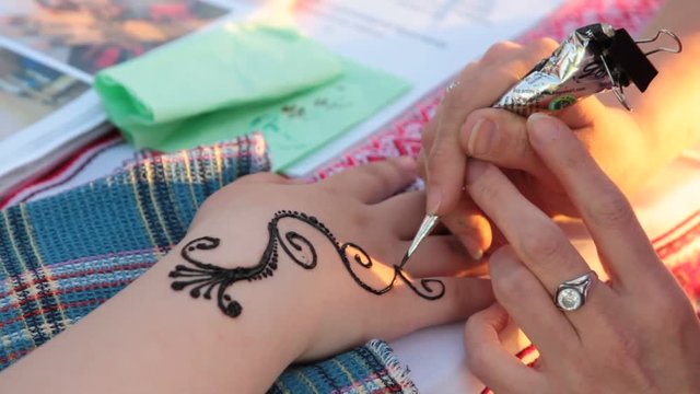 Drawing process of henna mehendi ornament on woman's back, close up kiev