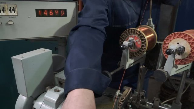 The worker places the coil with copper wire in the winding machine. Electric motor repair.