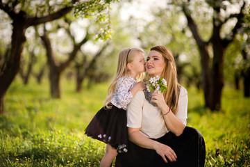 Obraz premium Little daughter gives her mother flowers for the holiday, a walk in the spring garden