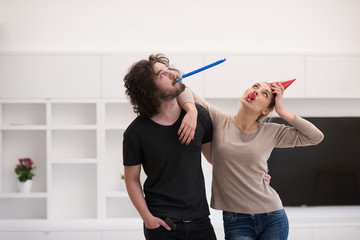 couple in party hats blowing in whistle