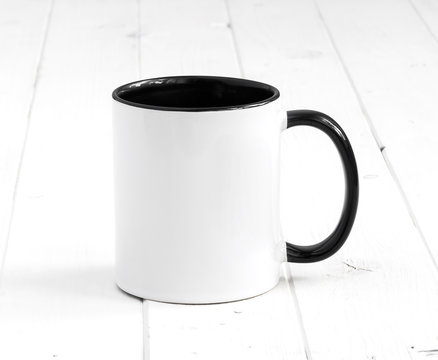 simple white cup with black inside and handle on a planked table