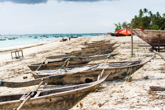 many old wooden fishing boats on african seashore with ocean on the background