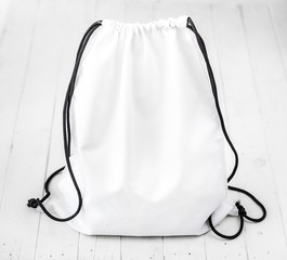 white backpack with black string on planked surface
