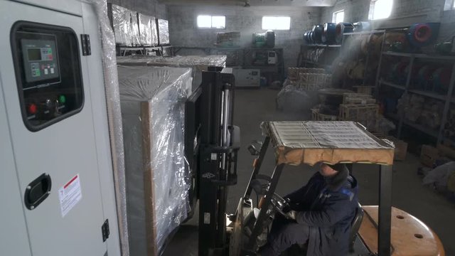 Diesel Forklift Truck lifts a large load nad leaves the warehouse. Working in the warehouse.