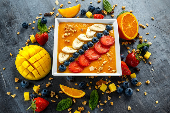 Fresh Orange Smoothie In Bowl For Breakfast With Blueberries, Granola, Mango, Strawberry And Banana