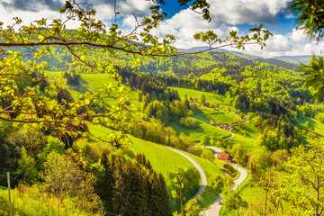 Scenic panoramic landscape of a picturesque mountain valley in spring. Scenic historic village with blossoming trees and traditional houses. Germany, Black Forest. Colourful travel background.