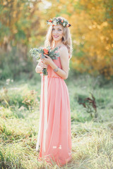 Fototapeta premium Bridesmaid with bouquet. Bridesmaid in pink dress looks into the camera.