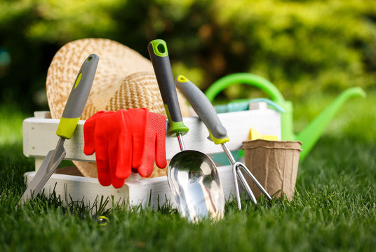 Gardening tools and a straw hat on the grass in the garden.