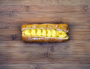 Custard donut on wooden background, plenty of text / design space.