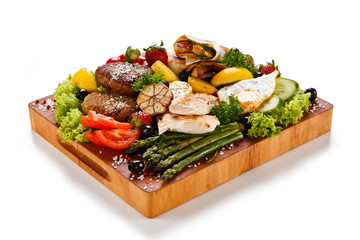Various meat and vegetables served on cutting board