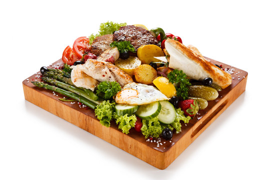Various meat and vegetables served on cutting board