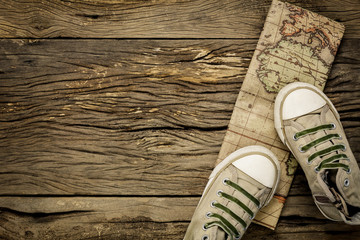 Top view essential travel items.The man shoes and vintage map on old rustic  wooden background with copy space.