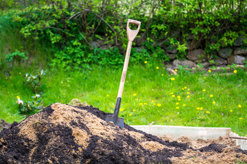 Shovel in pile of dirt and soil in a garden in spring