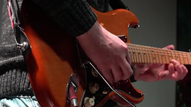 The man is masterly playing an electric guitar at a rock concert. close-up. In slow motion.