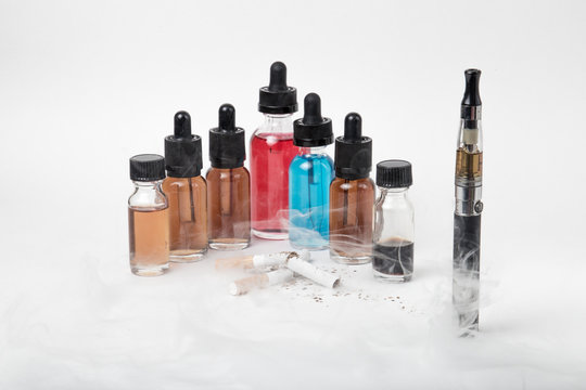 Broken tobacco cigarettes with modern electronic cigarette and e-juice bottles with smoke