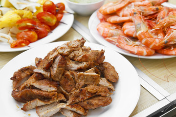 grilled pork and shrimp with vegetable barbecue BBQ and seafood sauce in white dish and wood table on summer holiday picnic for dinner food