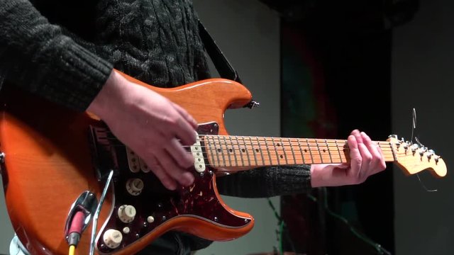 The man is masterly playing an electric guitar at a rock concert. close-up.