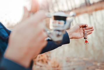 Young angler enjoys in fishing on the river. Close up photo of fisherman hands. Sport, recreation, lifestyle