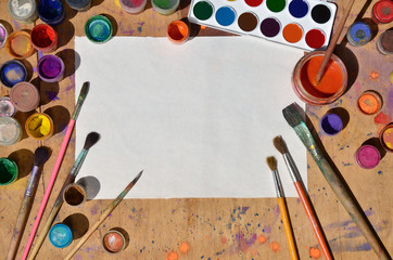 Still life with blank paper, brushes and jars of watercolor and gouache paint