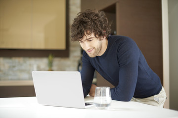 Home office. Shot of a confident young man using laptop while working from home. 