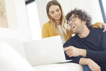 Shopping online. Shot of a lovely young couple relaxing on the couch and using a laptop at home