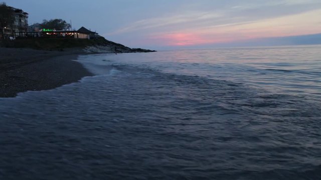 Waves gently wash up onto the beach, then recede as the sunset. A beautiful sunset over a sea akcakoca in Turkey