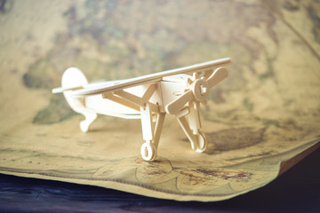 Wooden toy airplane flies on world map background in retro style