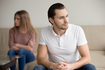 Sad handsome man thinking over problem, taking responsibility, finding compromise, frustrated couple after fight not talking ignoring, stubborn offended girlfriend sitting apart, unsupportive partner