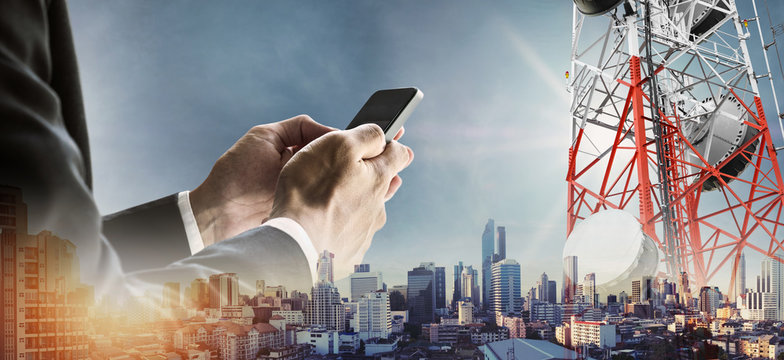 Businessman using smartphone with double exposure modern cityscape in sunrise, and telecommunication towers