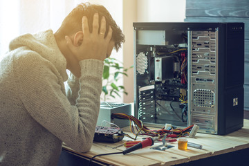 Man repairman broke the computer that was repaired in the service is on a workplace in the office