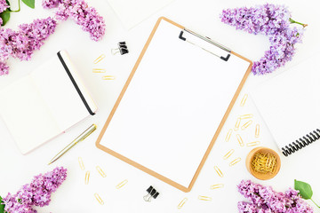 Minimalistic workspace with clipboard, notebook, pen, lilac and accessories on white background. Flat lay, top view. Beauty blog concept.