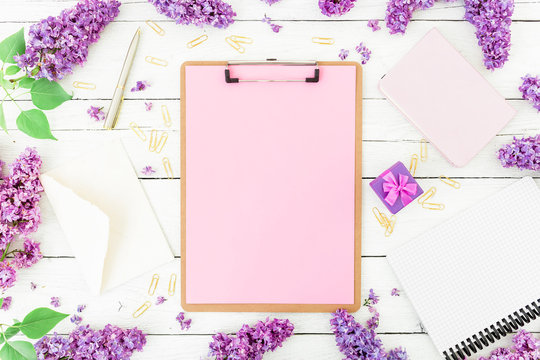 Minimalistic workspace with clipboard, envelope, pen, lilac, box and accessories on white background. Flat lay, top view. Freelancer or blogger concept.