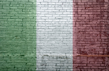 Italian flag over an old dirty brick wall