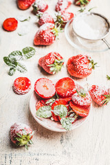 Fresh sliced Strawberries with powdered sugar on light rustic background, top view