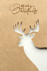 Merry christmas / Creative concept photo of a deer made of paper on brown background.
