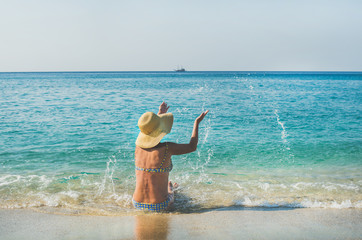 Beautiful slim senior woman tourist in bikini sitting on sand enjoying sea at Meditteranean resort of Turkey in Alanya, Kleopatra beach