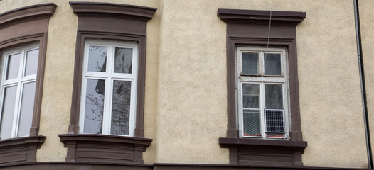 Fototapeta na wymiar Three white windows on the beige facade of the house