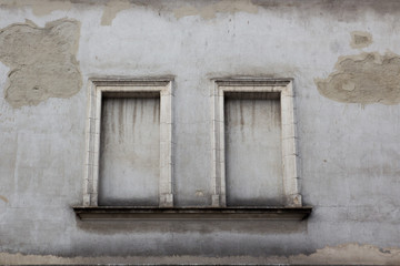 Two concreted windows on the facade of the old gray house