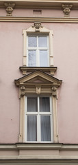Two white vintage design windows on the facade of the old house